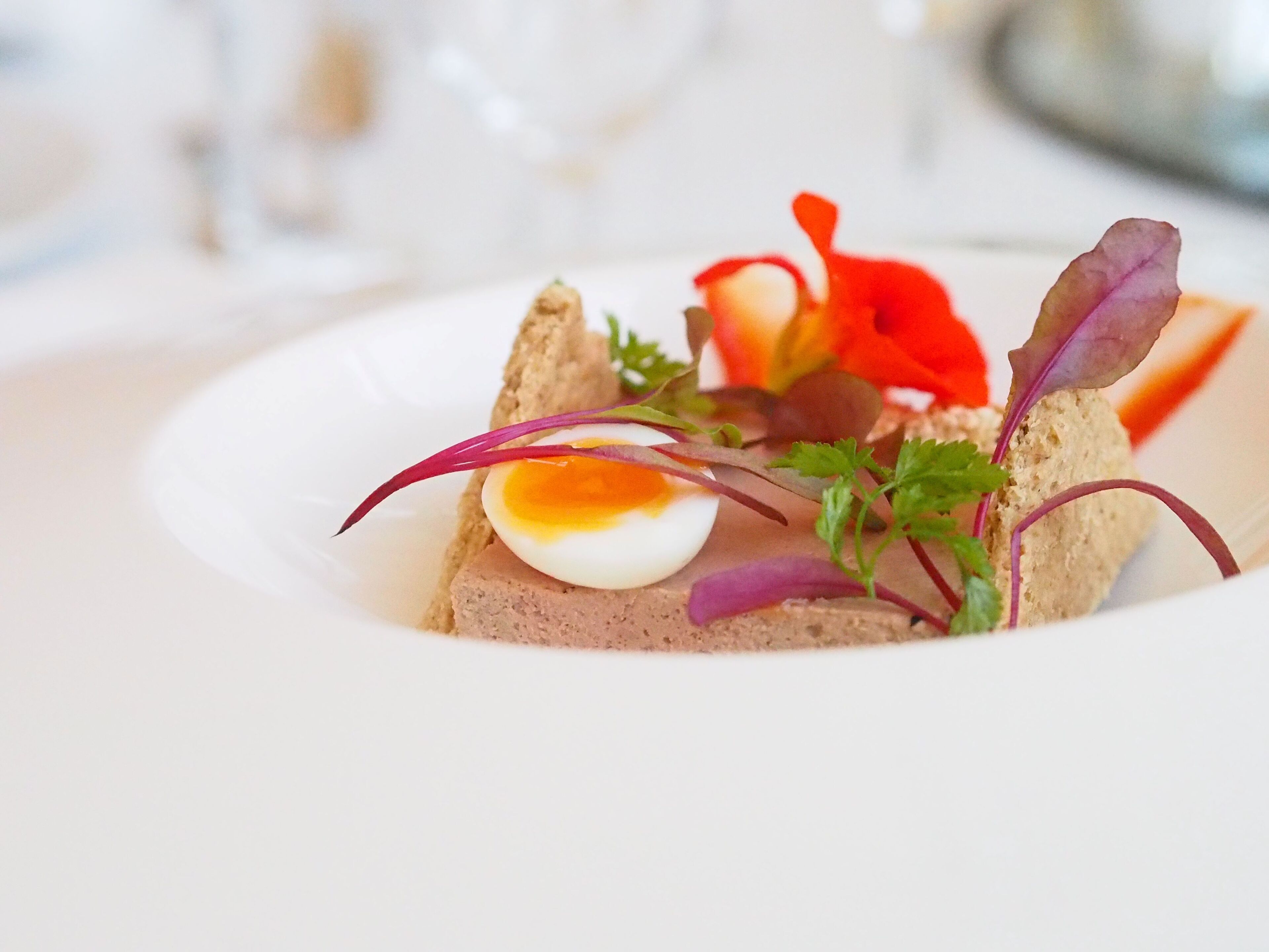 Un plato con una rebanada de pan, un huevo cocido y guarniciones variadas.