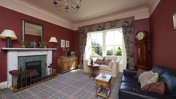 A living room with a fireplace, a sofa, a coffee table, and a clock on the wall.