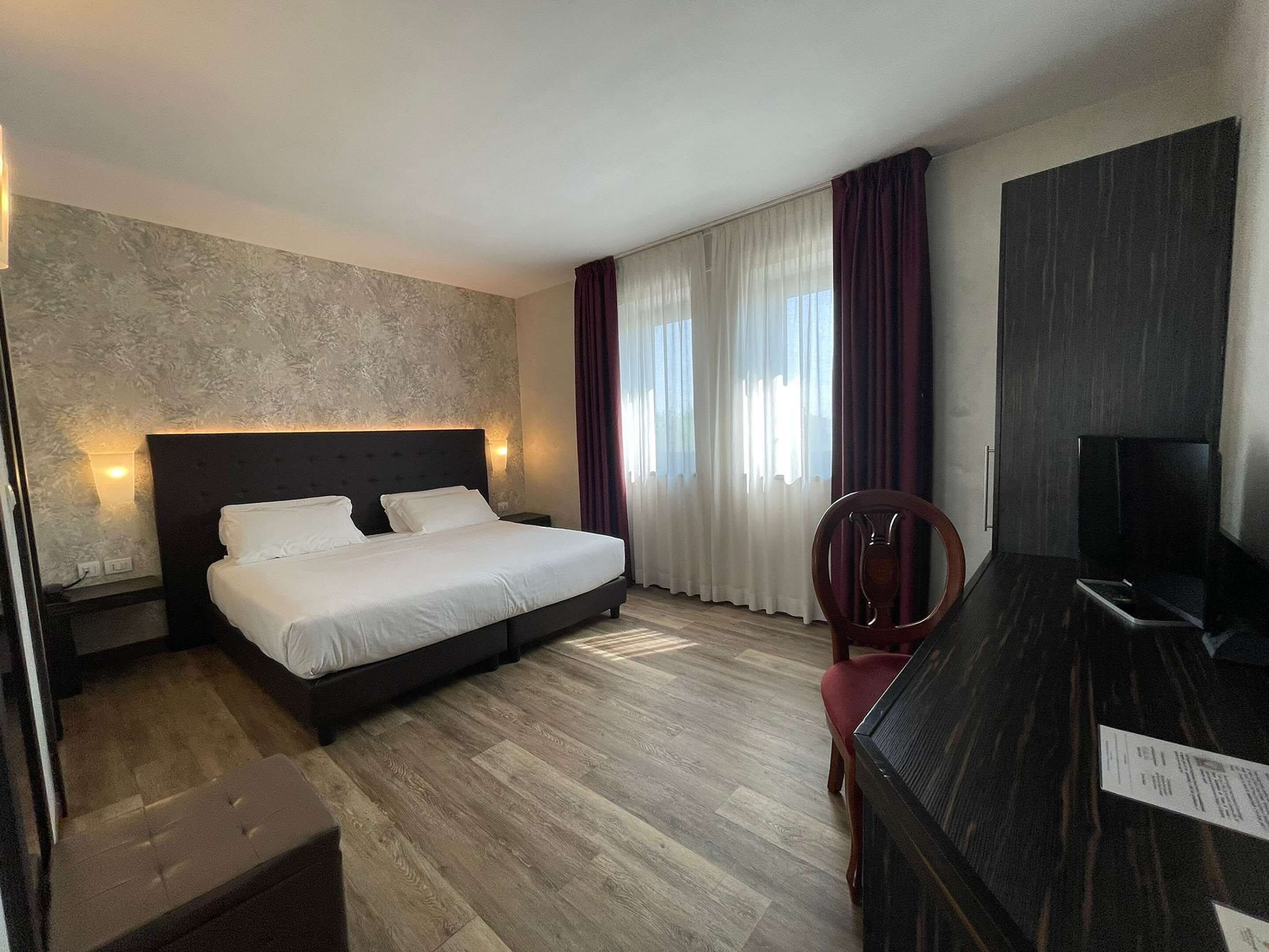 Ein Hotelzimmer mit Bett, Schreibtisch, Sessel und Fernseher.