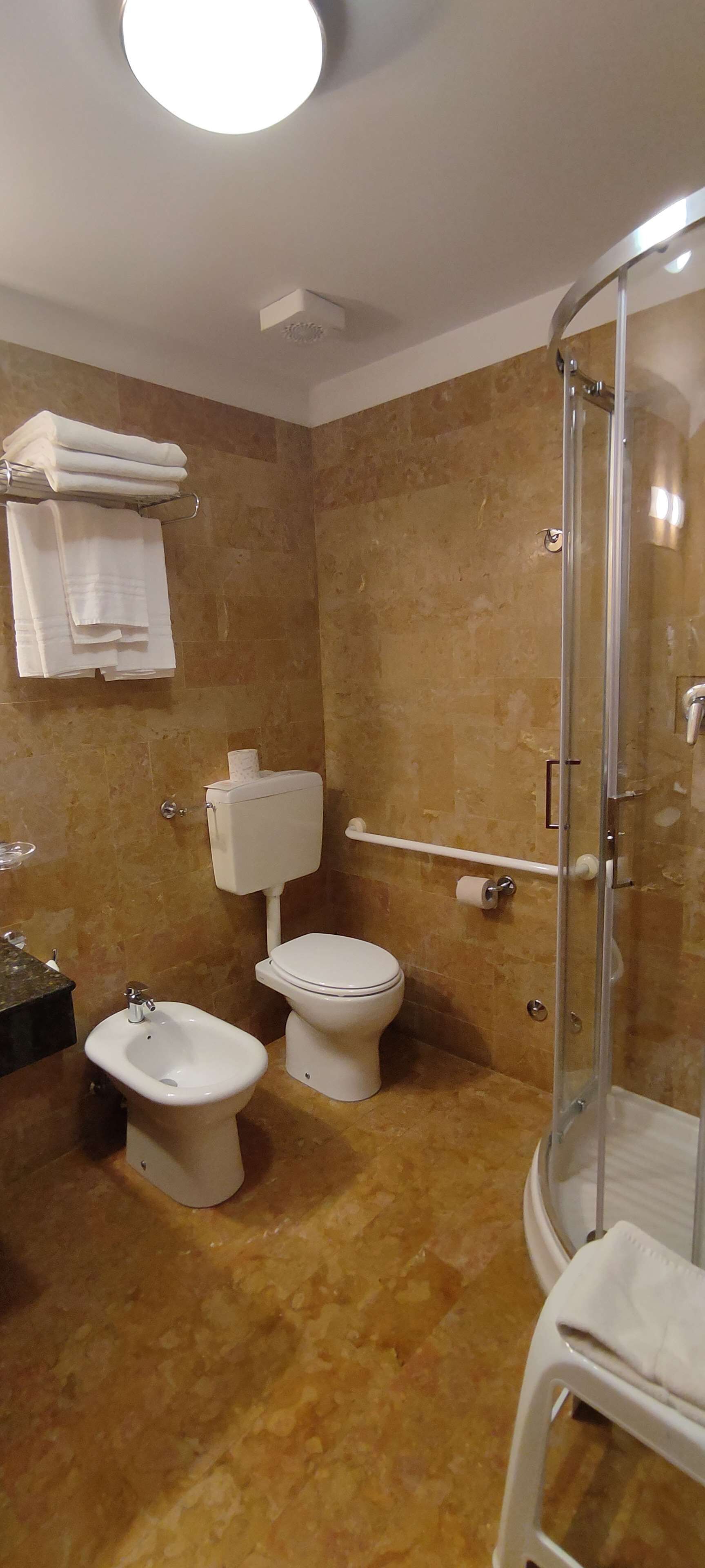 A bathroom with two toilets, a bidet, a shower, and a sink.