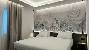 A modern bedroom with a large bed, a headboard with a leaf pattern, and a nightstand with a lamp. - Best Western Park Hotel Continental (San Dona di Piave)