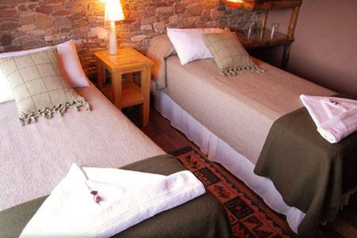 Two single beds with pillows and a small wooden nightstand between them.