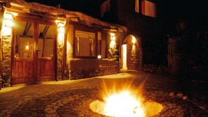 A stone building with a thatched roof, a fire pit in the center, and a wooden door. - Refugio Del Pintor (Tilcara)