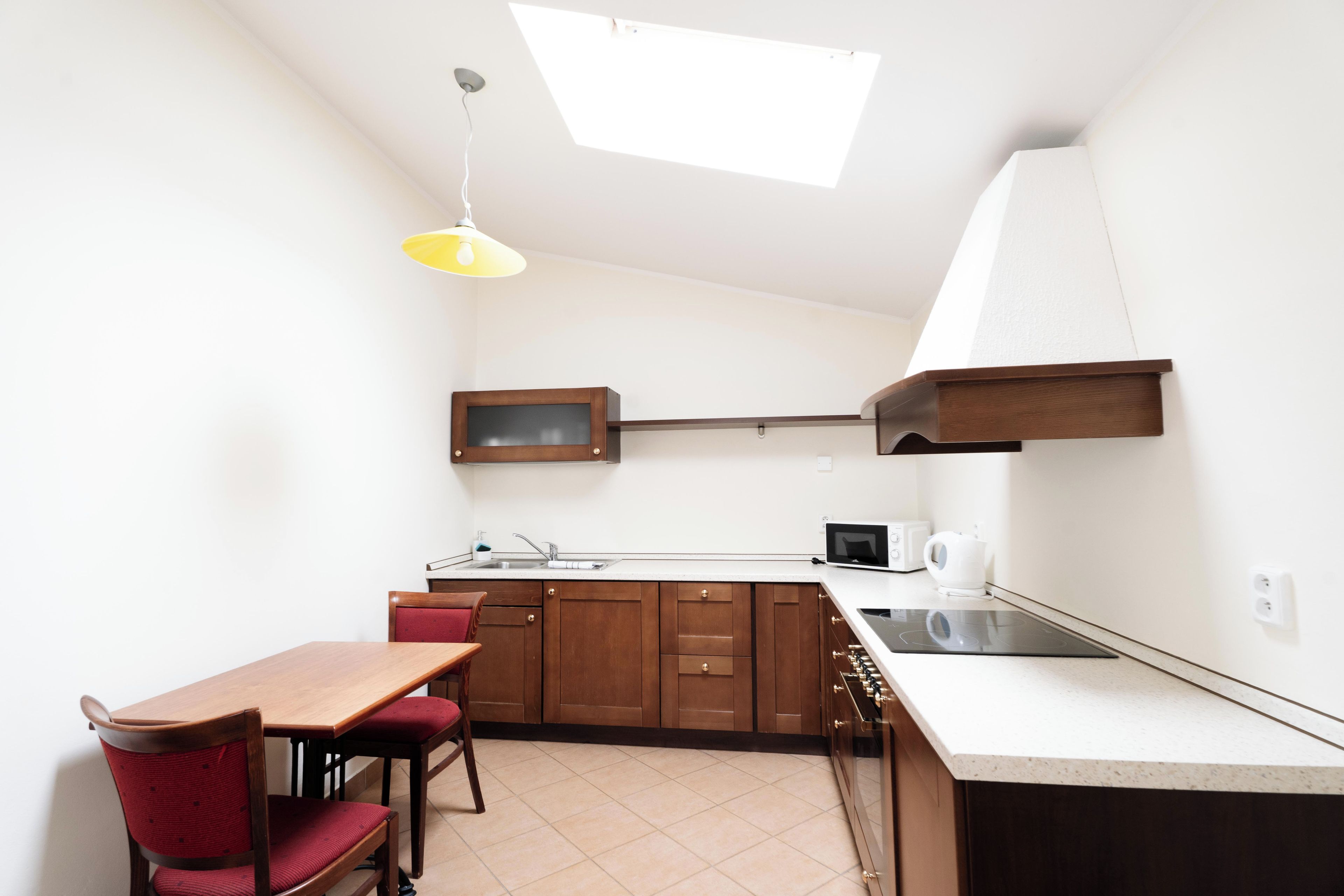 A compact kitchen with a dining area, a built-in microwave, and a small window for natural light.
