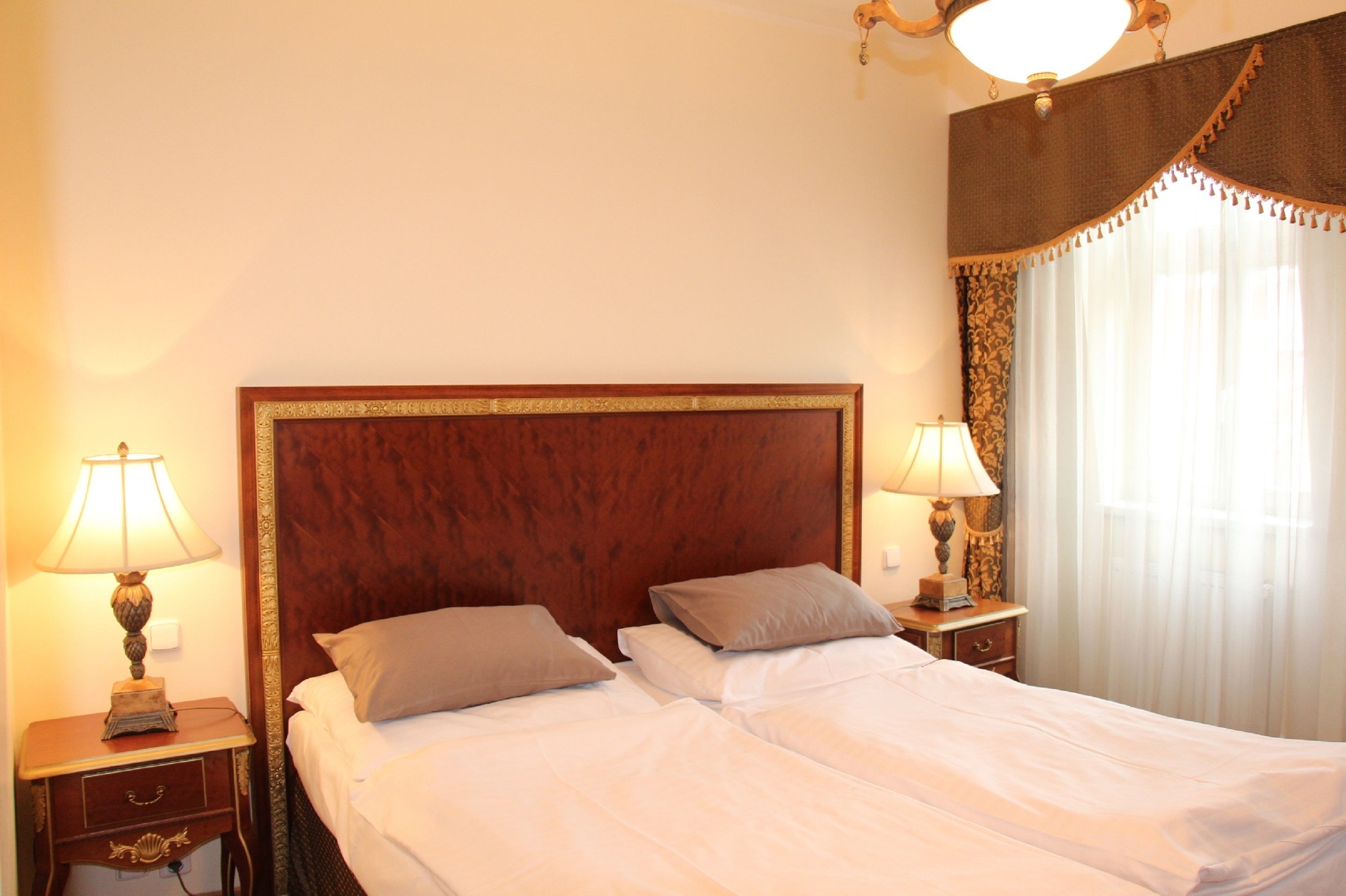A hotel room with a large bed, two bedside tables with lamps, and a window with curtains.