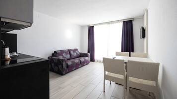 A modern, minimalist living room with a sofa, dining table, and chairs.