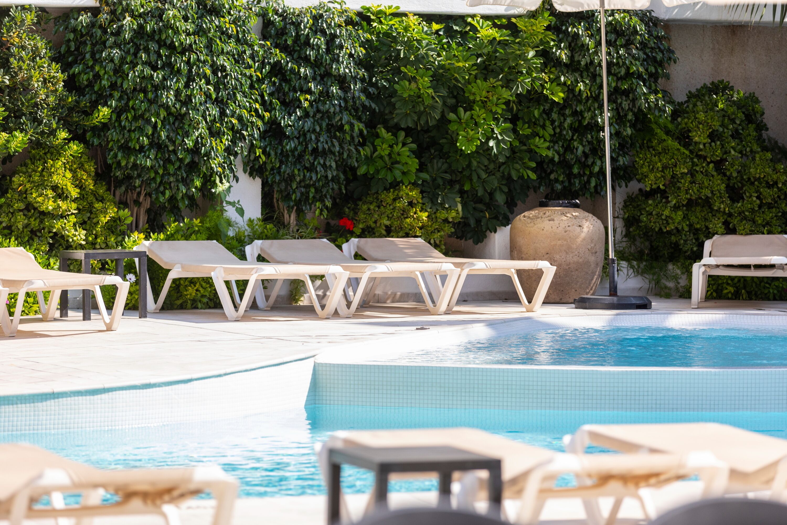 Un área de piscina con sillas de descanso y un elemento decorativo de piedra.