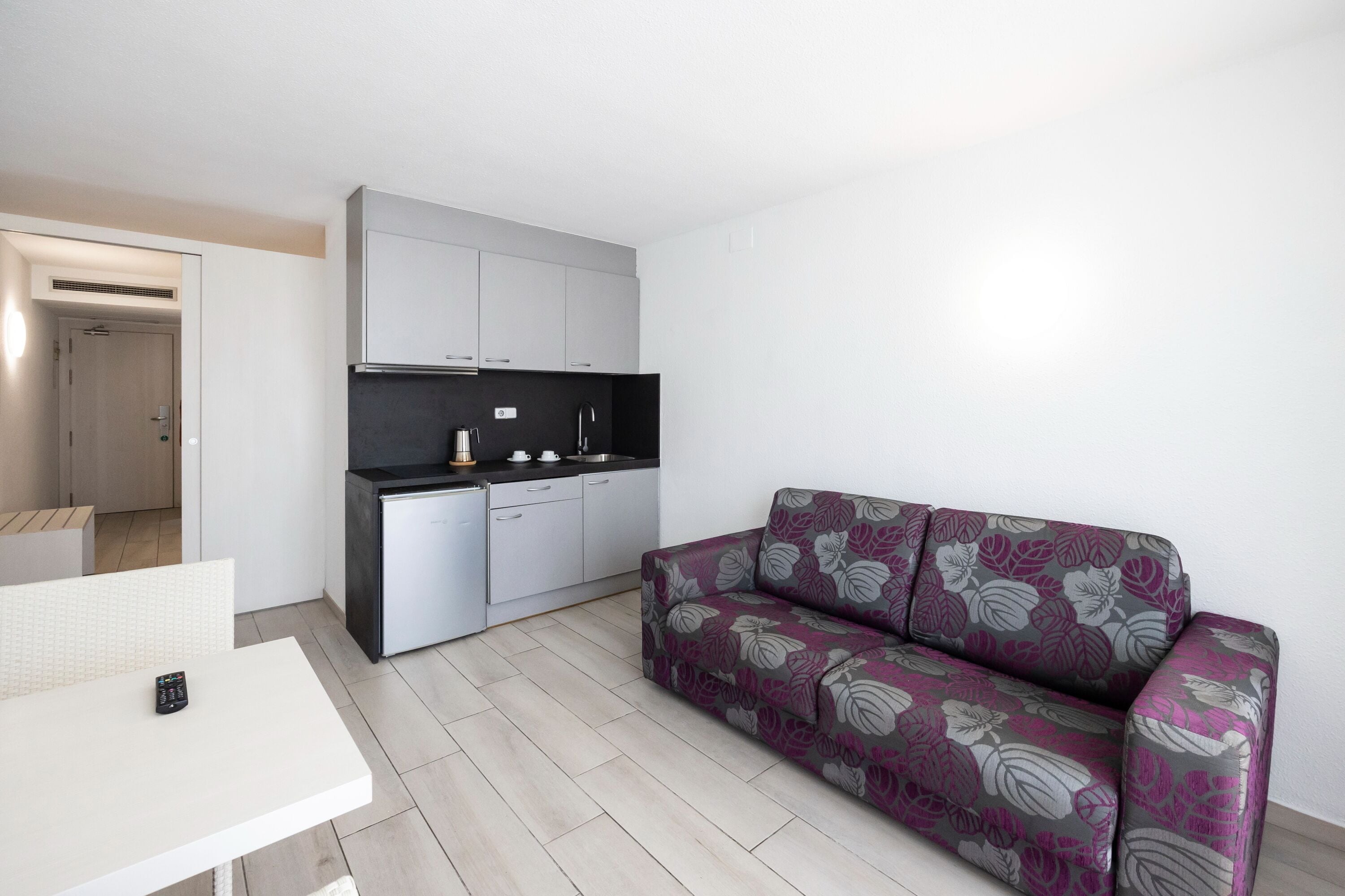 Una sala de estar moderna con un sofá, una mesita y una kitchenette.