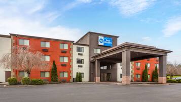 Un hotel con fachada roja y color beige, una entrada techada y un letrero que indica que pertenece a la cadena Best Western.