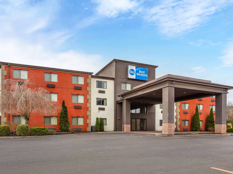 A hotel with a red and beige exterior, a covered entrance, and a sign indicating it is part of the Best Western chain.