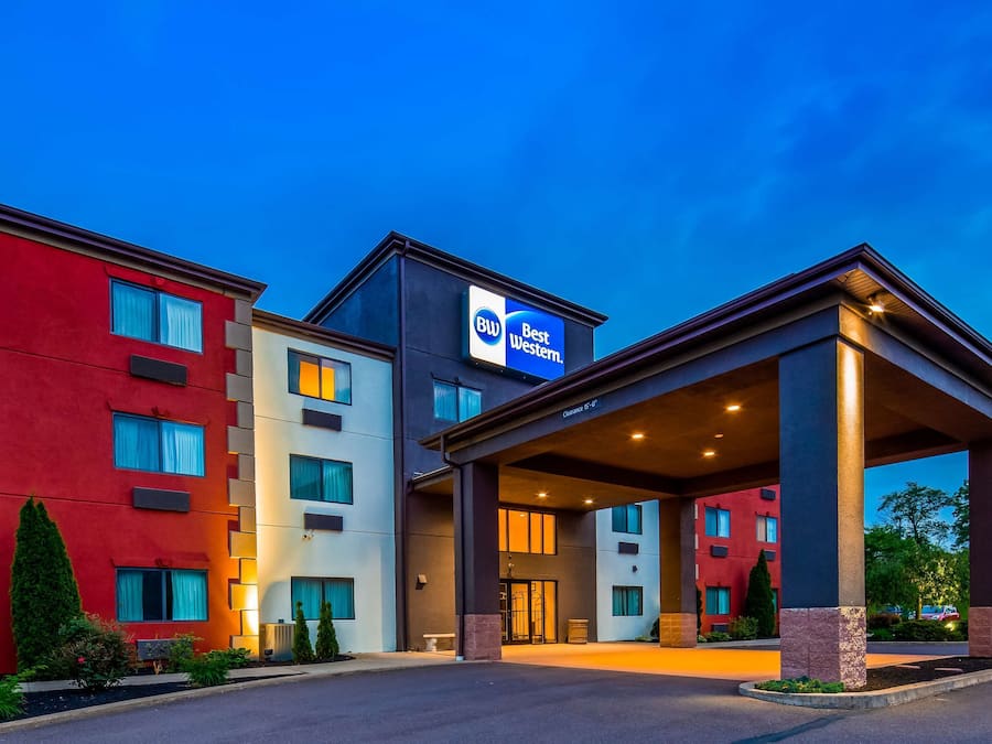 Un hotel Best Western con fachada roja y blanca, una entrada cubierta y cielo despejado.