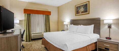A hotel room with a large bed, a television, a desk, and a nightstand.