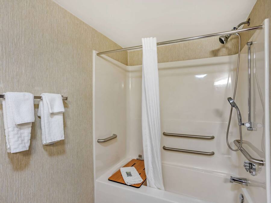 Un baño moderno con bañera, ducha y barras de apoyo.