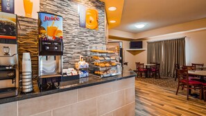 A breakfast area with a juice dispenser, a coffee machine, and a display of pastries and donuts. - Best Western Danville Inn (Danville)