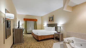 Una habitación de hotel con cama, escritorio, silla, baño con bañera y espejo.