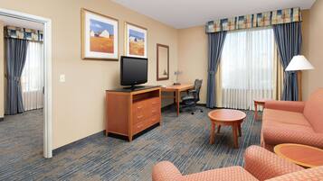 Habitación de hotel con escritorio, televisión, sofá y sillón.
