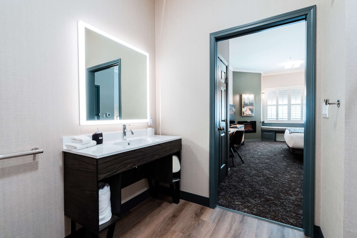 Un baño moderno con tocador de doble lavabo, un espejo grande y un mueble de madera oscura.