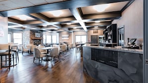 A spacious dining area with wooden flooring, modern furniture, and a stone fireplace.
