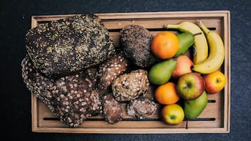 Un plateau en bois contenant divers aliments, notamment du pain, des fruits et des légumes.