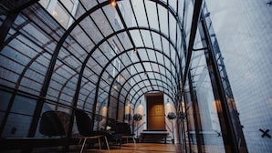 A modern interior with a curved glass ceiling, wooden flooring, and a piano.