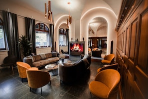 A spacious living room with a fireplace, comfortable seating, and a view of the city. - Ascot Apartments (Copenhagen)
