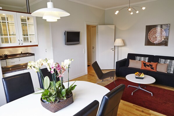 Una sala moderna con una mesa de comedor, sillas, un sofá y un televisor.