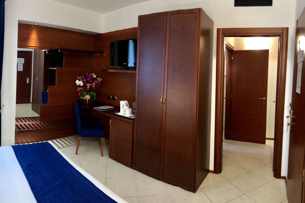 A hotel room with a bed, a desk, a TV, and a wardrobe.