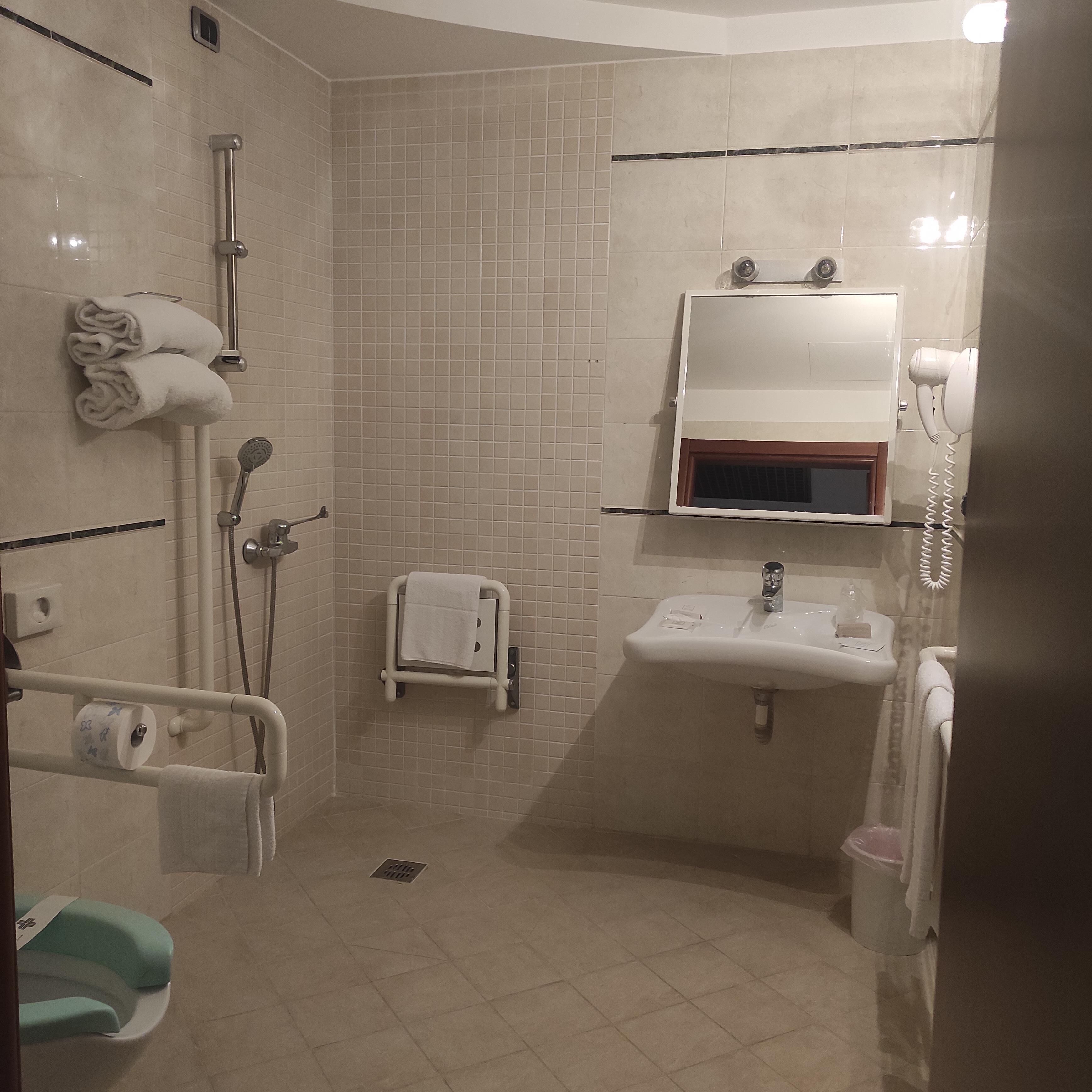 A bathroom with a shower, a sink, a toilet, and a towel rack.