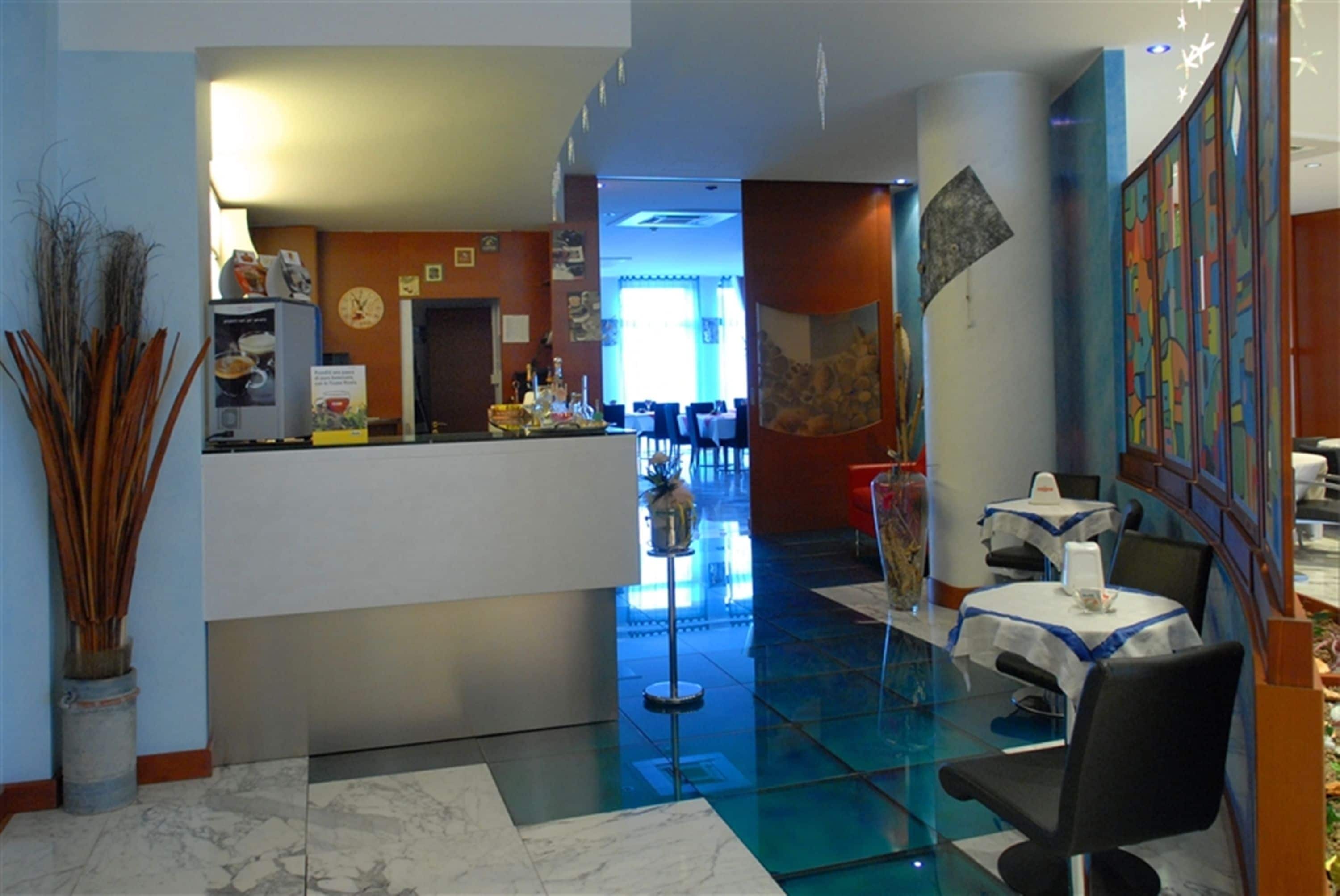 A hotel lobby with a reception desk, seating area, and a view of the dining area.
