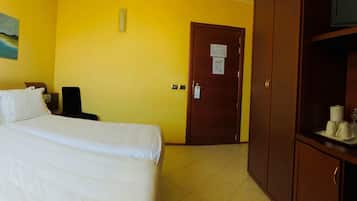 Habitación de hotel con cama, escritorio con teléfono, televisor y un cuadro en la pared.