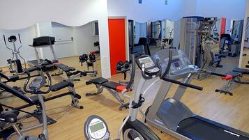 Una palestra con diverse attrezzature per l'allenamento, tra cui tapis roulant, cyclette e macchinari per pesi.