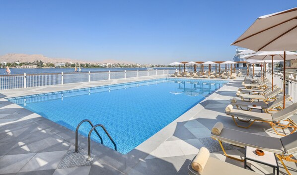 A swimming pool with a view of the sea and a cityscape in the background.