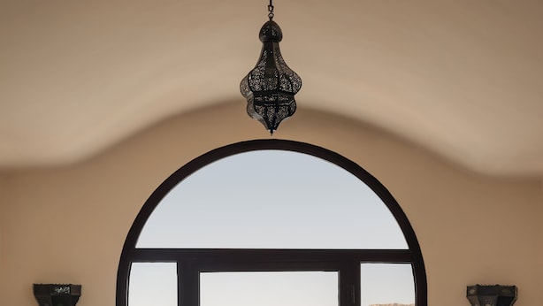 A dining area with a table set for two, overlooking a body of water and hills. - Iberotel Luxor by JAZ (Luxor)
