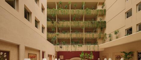 Un vestíbulo amplio con varias zonas de estar, una mesa central y un jardín en el techo.