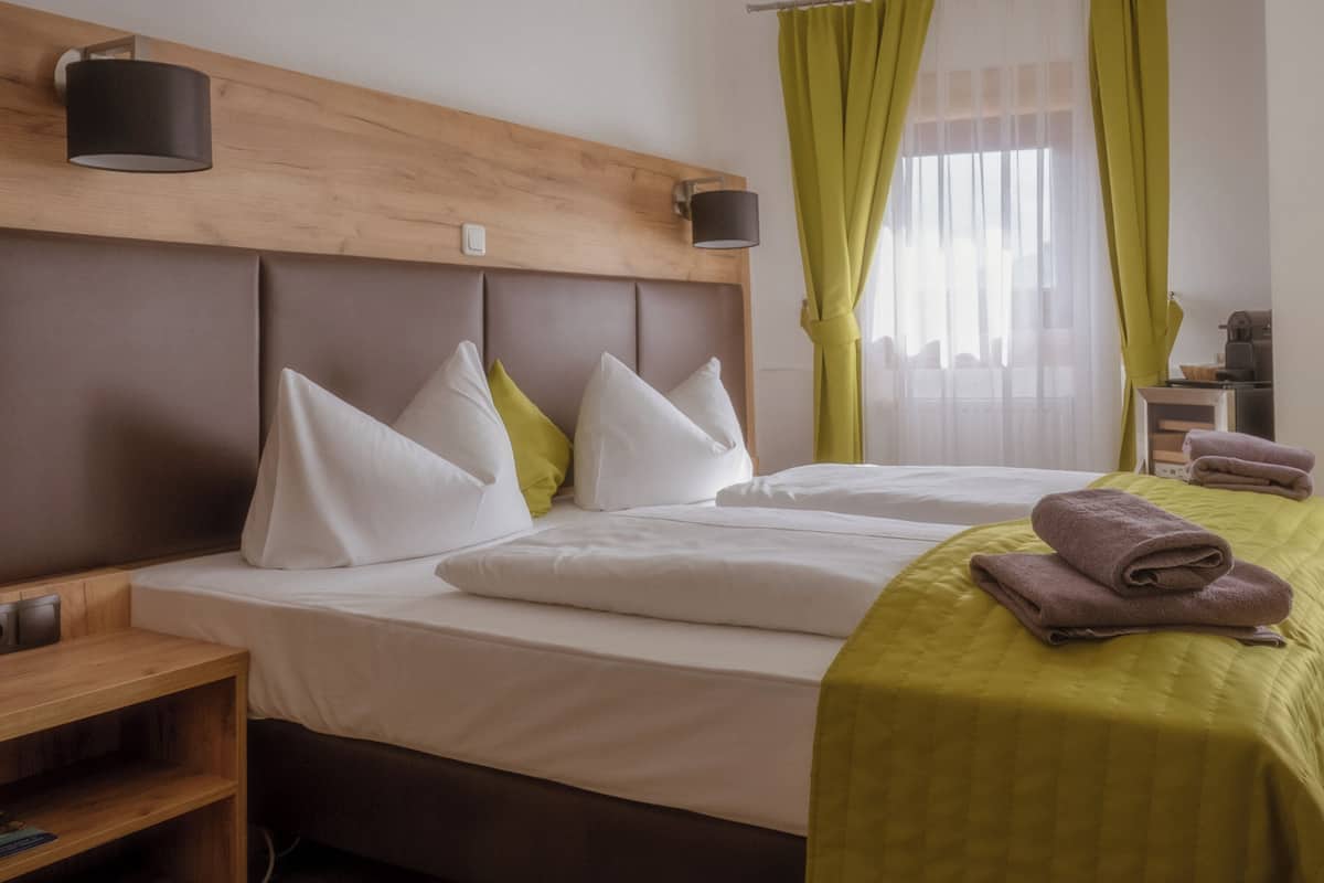 Een hotelkamer met twee bedden, een houten hoofdeinde, een nachtkastje en een lamp.
