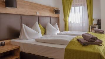 Una habitación de hotel con dos camas, un cabecero de madera, una mesita de noche y una lámpara.