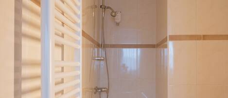 A bathroom with a bathtub, a shower, and a radiator.