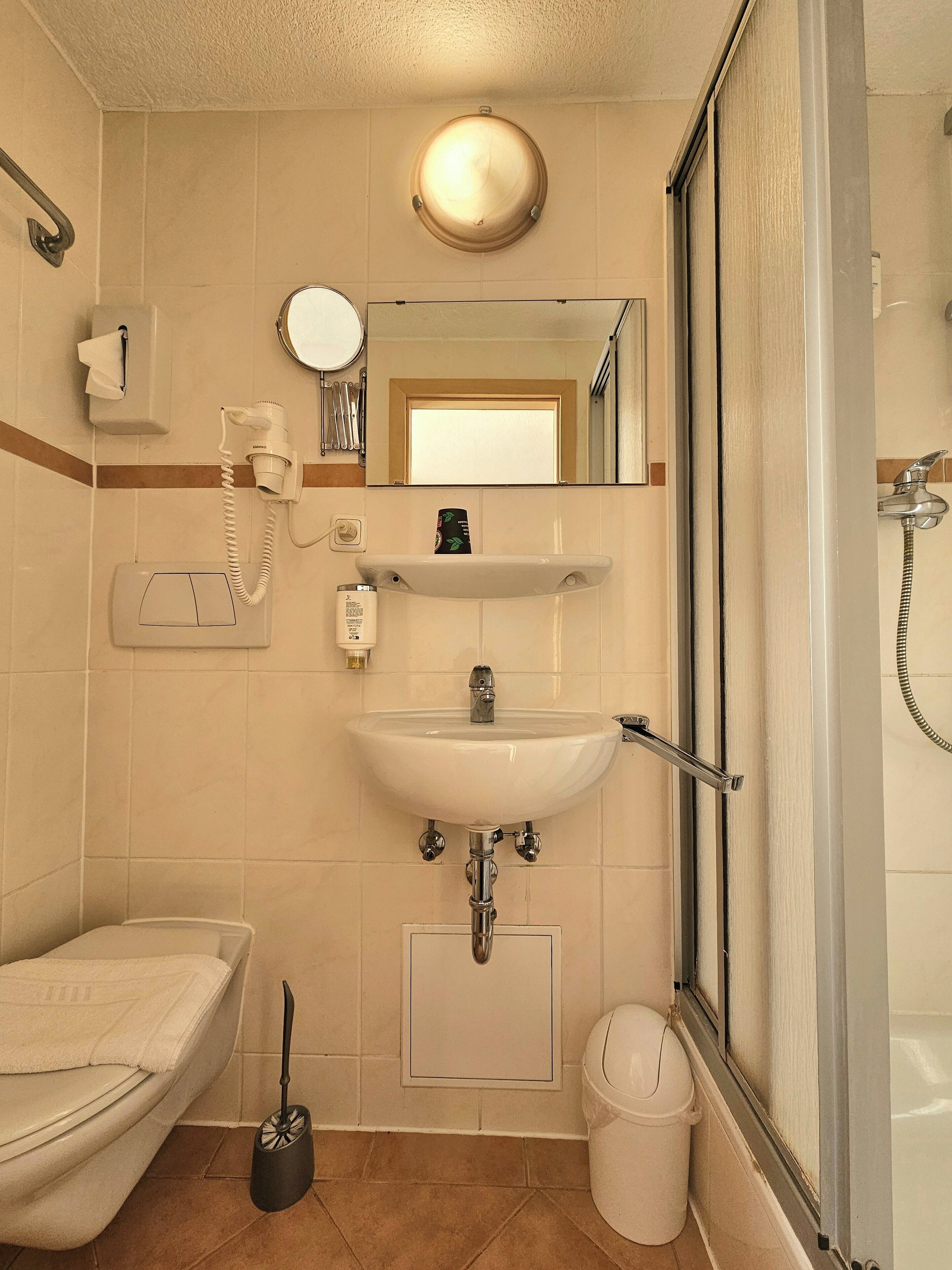 Un baño con inodoro, lavabo, espejo y ducha.