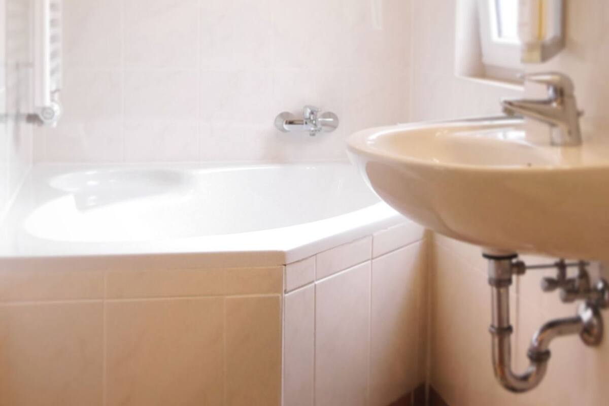 Een badkamer met een bad, een wastafel en een raam.