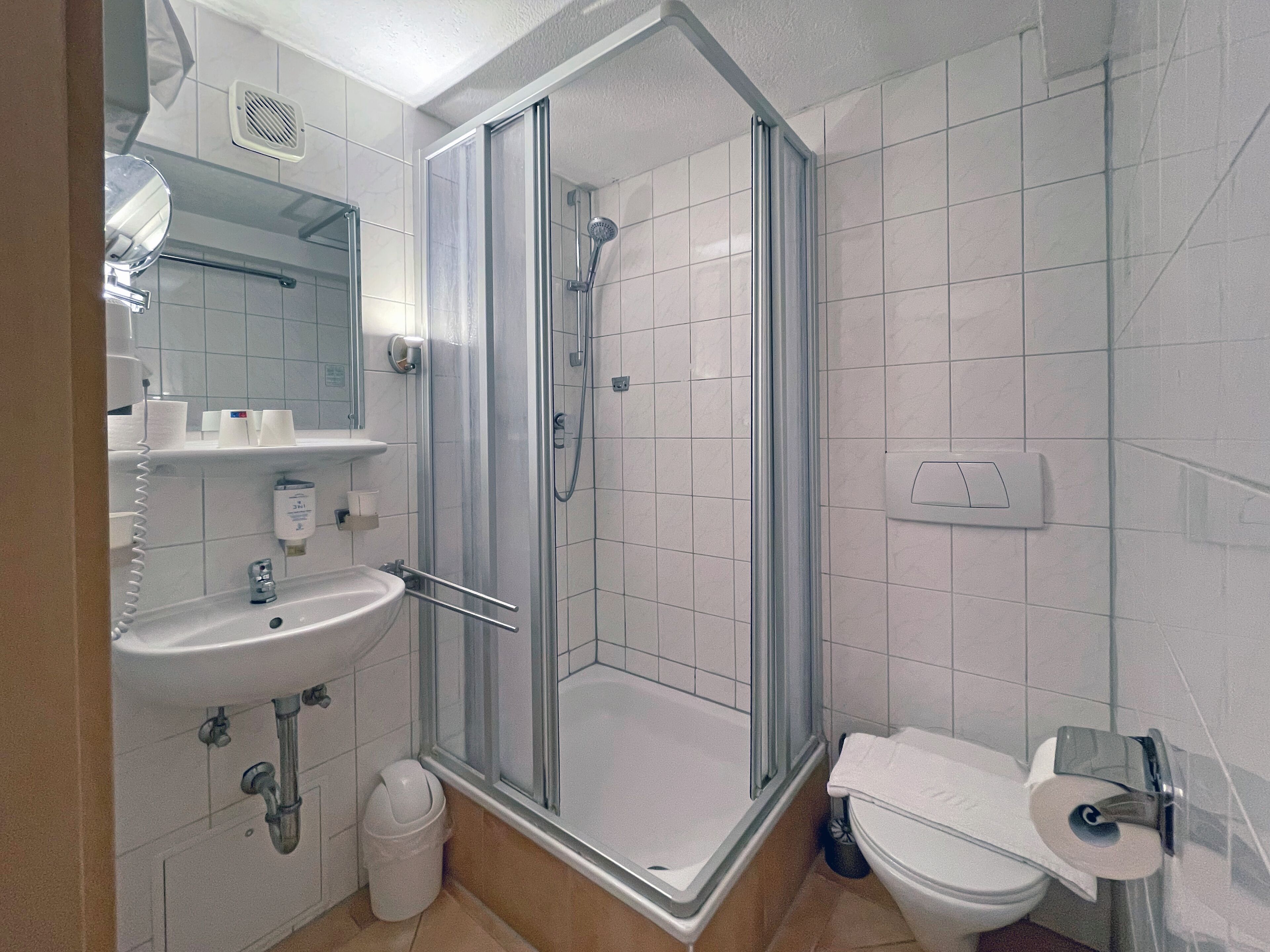 A modern bathroom with a glass-enclosed shower, a sink, and a toilet.