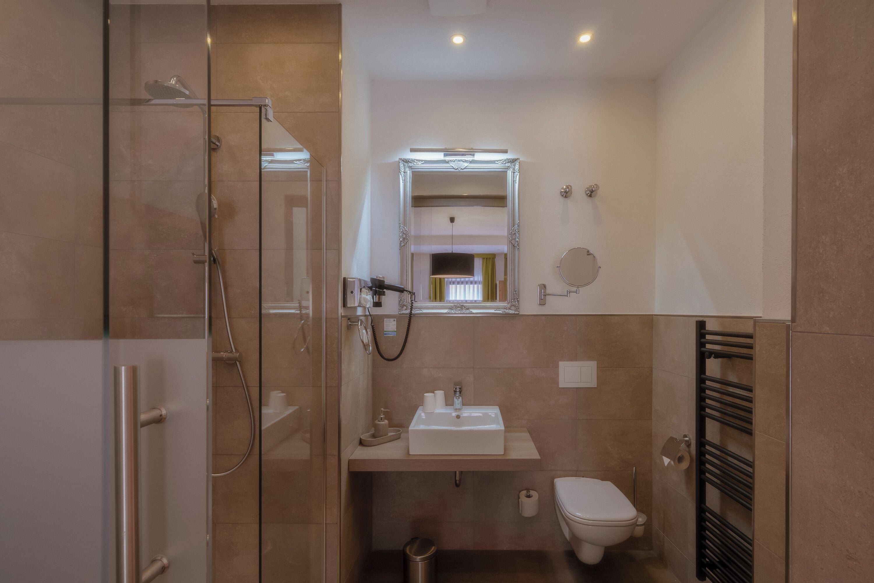 Un bagno moderno con box doccia in vetro, un lavandino bianco con specchio sopra e un water con portasciuga.