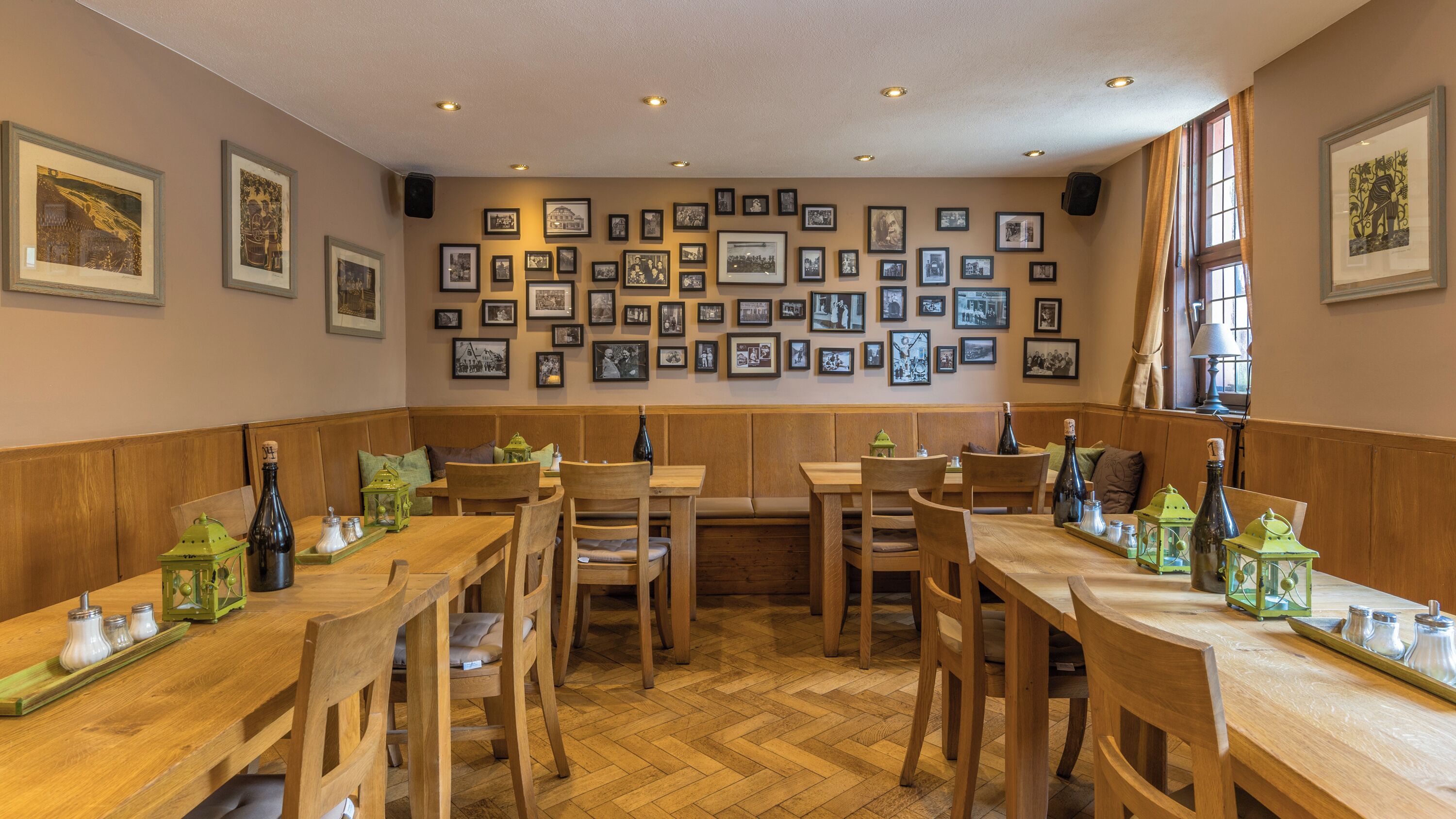 Un ristorante con tavoli e panche in legno, quadri appesi alle pareti e un pavimento a spina di pesce.
