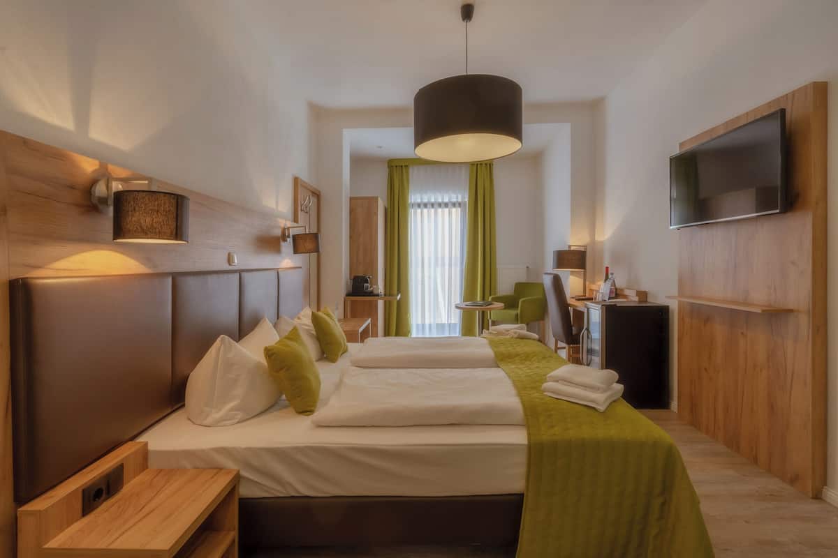 Een moderne hotelkamer met een groot bed, een aan de muur bevestigde televisie en een klein bureau.