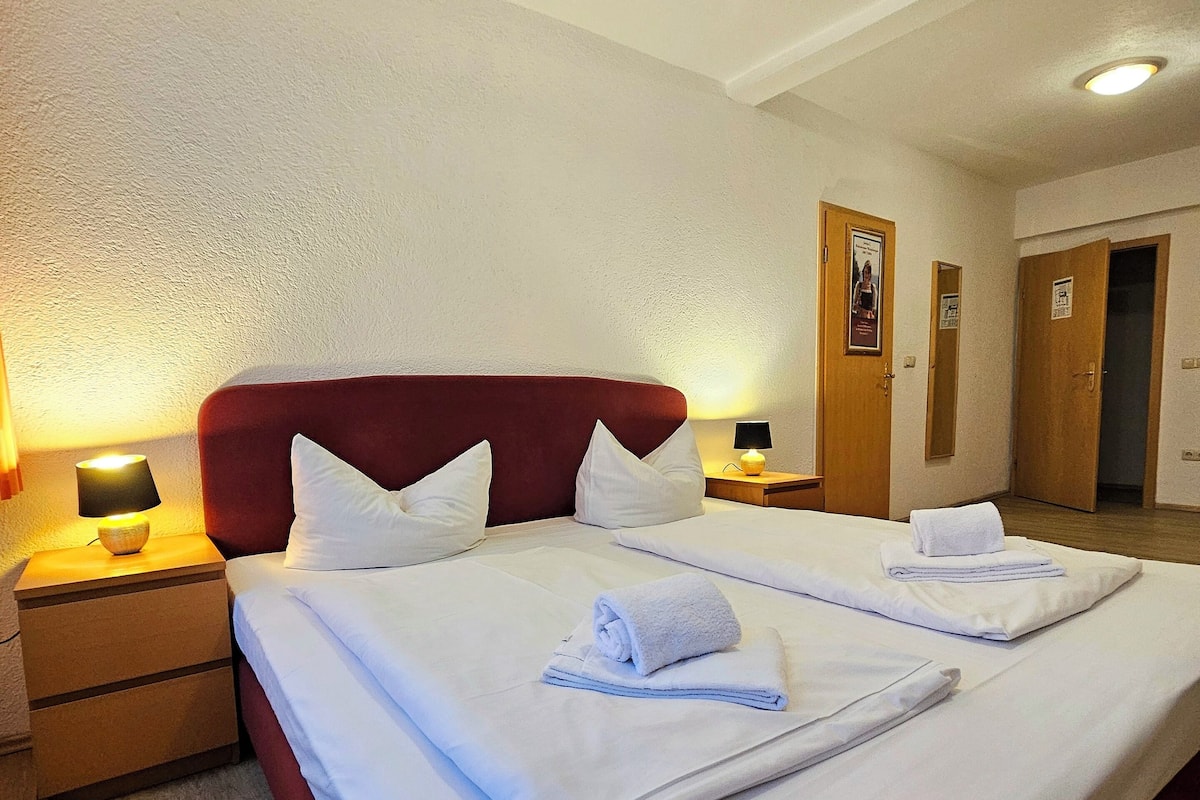 Een hotelkamer met een groot bed, twee nachtkastjes met lampen en een houten vloer.