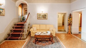 A living room with a staircase, a sofa, a coffee table, and a rug. - Dimora Casa Eugenia (Loro Ciuffenna)