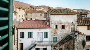 A traditional European town with stone buildings, a visible staircase, and a clear view of the surrounding hills. - Dimora Casa Eugenia (Loro Ciuffenna)