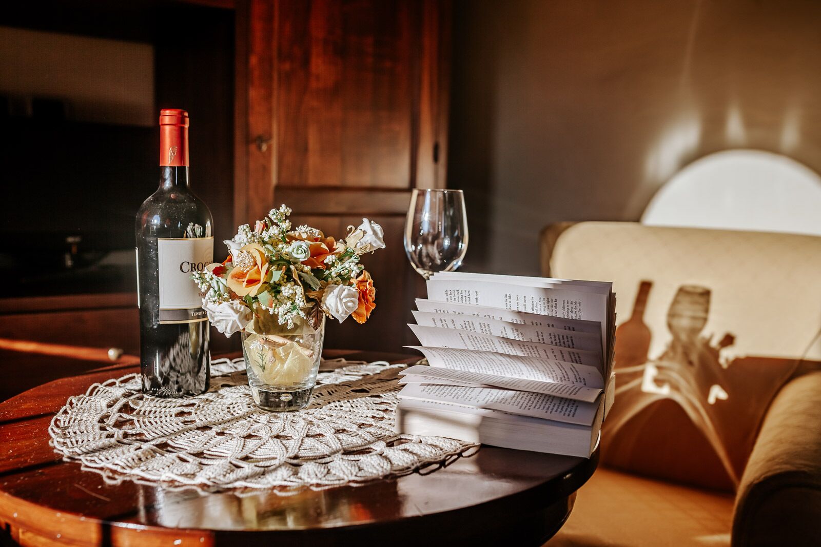 A table with a wine bottle, a glass, a vase with flowers, and a menu.