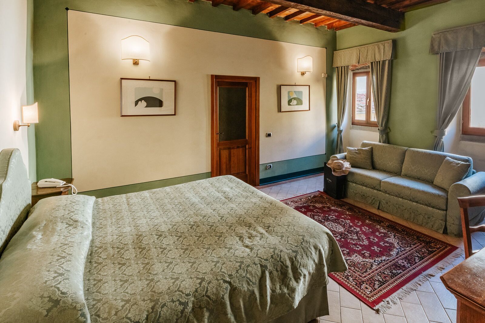 Une chambre à coucher avec un lit, un canapé, une petite table et une porte.