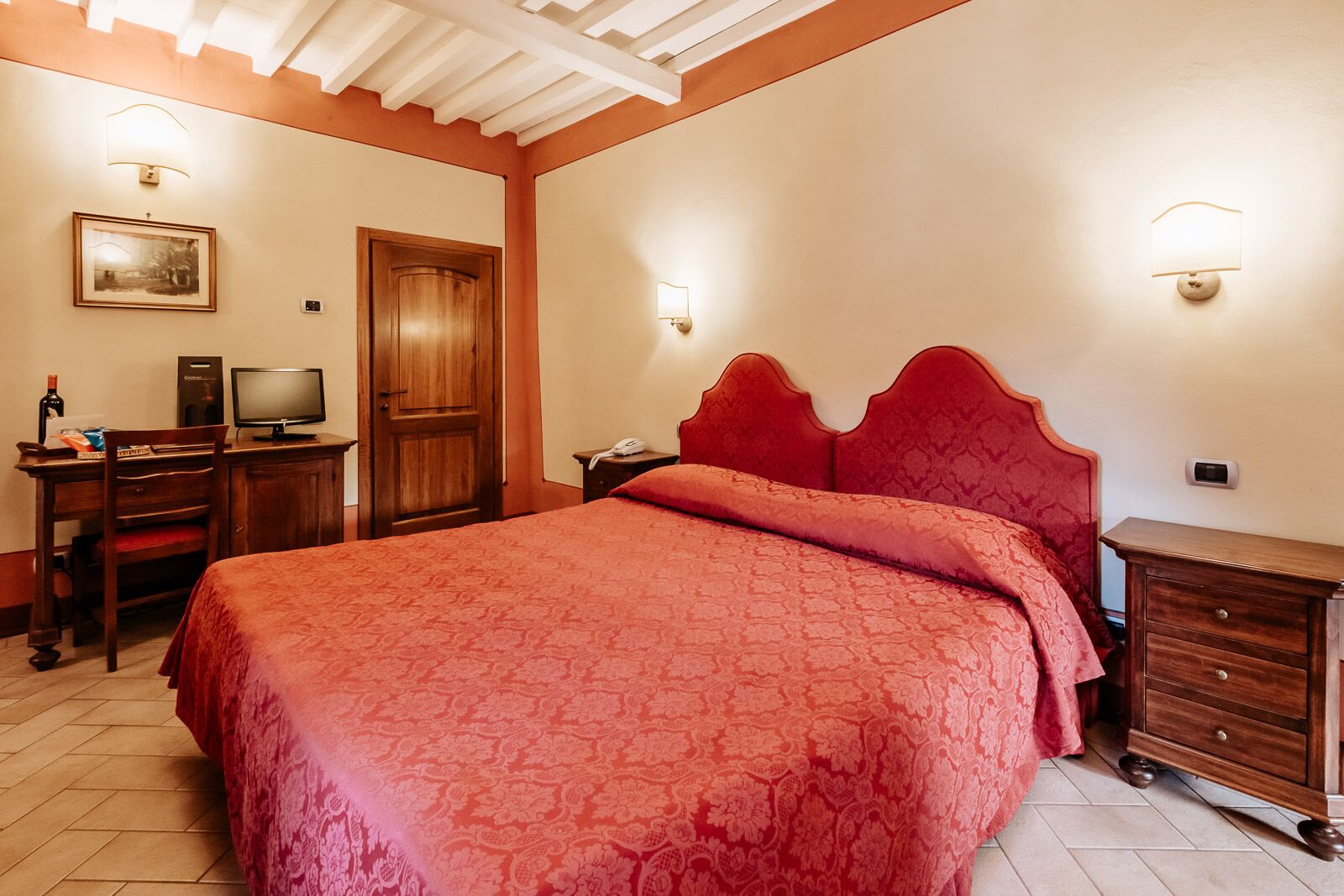Une chambre à coucher avec un grand lit, un bureau avec un ordinateur, une chaise et une armoire en bois.