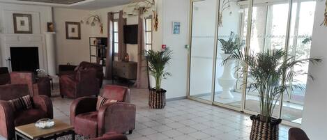 Un salón amplio con sofás de cuero, una chimenea y grandes macetas con plantas.